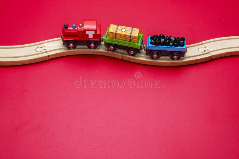 Toy train with curved wooden railways on red background. Wooden locomotive. Toy wooden train move on railway stock photo Toy train with curved wooden railways on red background. Wooden locomotive. Toy wooden train move on railway stock photo