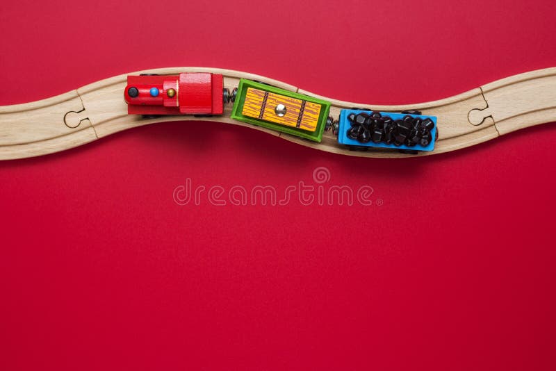 Toy train with curved wooden railways on red background. Wooden locomotive. Toy wooden train move on railway royalty free stock image Toy train with curved wooden railways on red background. Wooden locomotive. Toy wooden train move on railway royalty free stock image