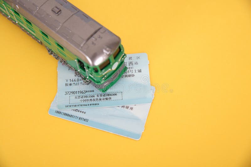 A Toy Train and Two Train Tickets on a Yellow Background Stock Photo