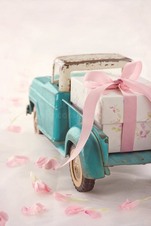 Toy truck carrying a gift box with pink ribbon