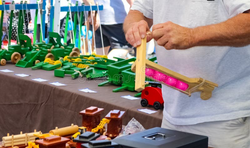 Toymakershanden die een houten stuk speelgoed in een cabine samenbrengen bij uit buitenkantfestival royalty-vrije stock foto Toymakershanden die een houten stuk speelgoed in een cabine samenbrengen bij uit buitenkantfestival royalty-vrije stock foto