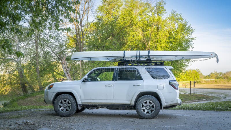 Blackwater, MO, USA - April 22, 2024: Toyota 4Runner SUV with an expedition canoe on roof racks at a shore of the Lamine River in spring scenery. Blackwater, MO, USA - April 22, 2024: Toyota 4Runner SUV with an expedition canoe on roof racks at a shore of the Lamine River in spring scenery