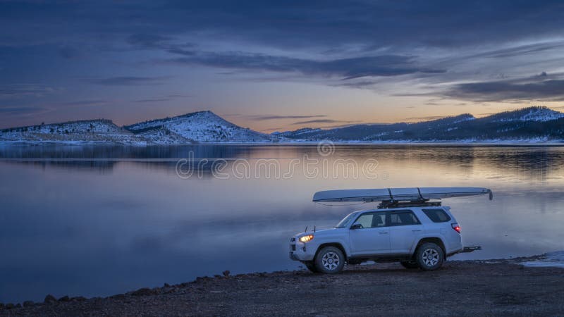 Toyota 4Runner внедорожник с экспедиционным каноэ на крыше стойки зимние пейзажи в сумерках на берегу стоковые изображения