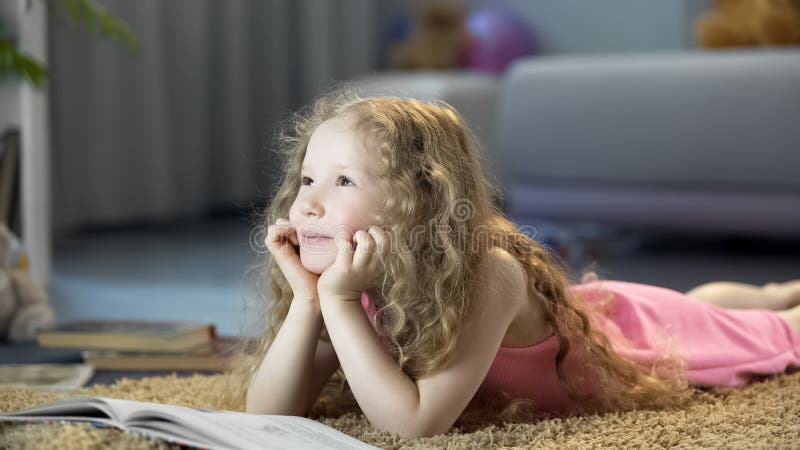 Tr?umerisches nettes M?dchen, das zu Hause auf Boden im gem?tlichen Raum, gl?ckliches Kinderdenken liegt stockfotos Tr?umerisches nettes M?dchen, das zu Hause auf Boden im gem?tlichen Raum, gl?ckliches Kinderdenken liegt stockfotos