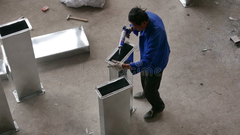 Trabajador asiático que calafatea el conducto de Aircon