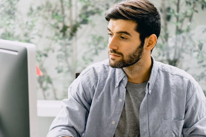 Trabajador caucásico con barba y bigote en camisa informal usando computadora de escritorio imágenes de archivo libres de regalías