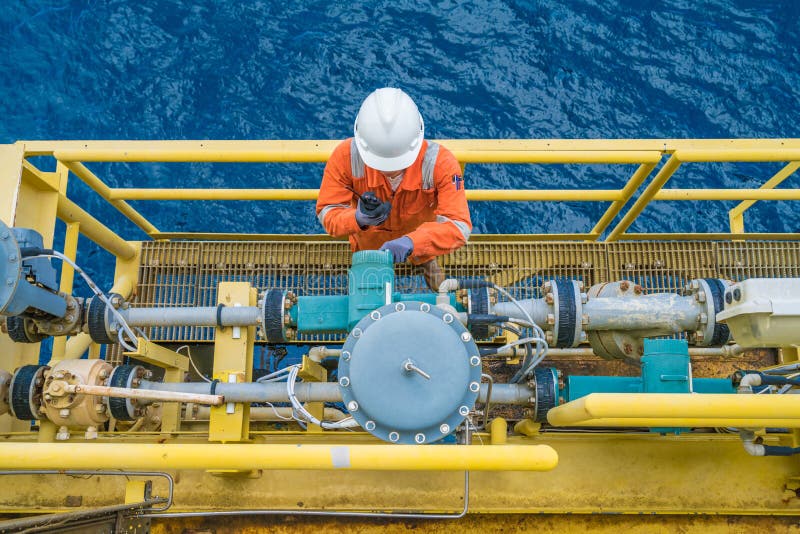 Trabajador costero de la plataforma petrolera que comprueba el parámetro del metro digital del transmisor de flujo de los corioli