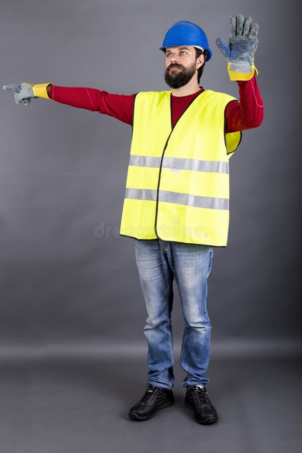 Trabajador de construcción joven con el tráfico de dirección del casco de protección, showin imagenes de archivo Trabajador de construcción joven con el tráfico de dirección del casco de protección, showin imagenes de archivo