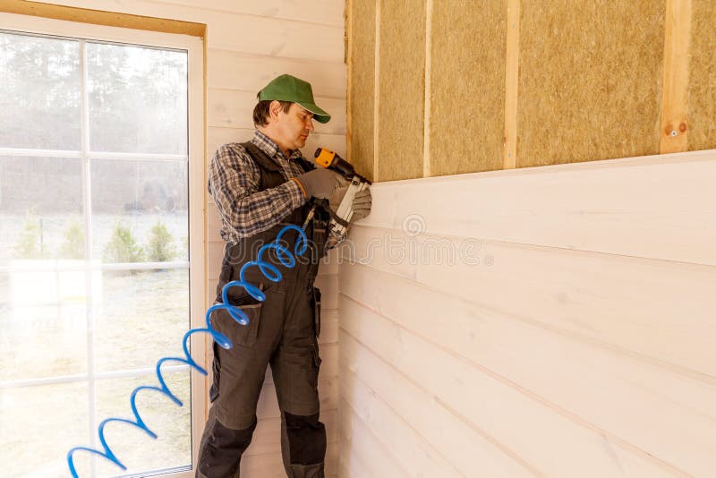 Trabajador de construcción que aísla termalmente la casa de marco de madera del eco foto de archivo Trabajador de construcción que aísla termalmente la casa de marco de madera del eco foto de archivo