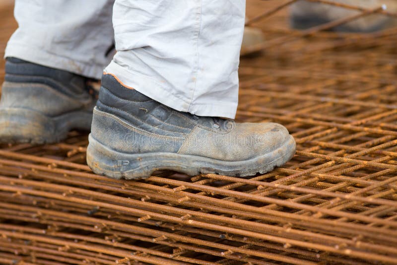 Trabajador de construcción que se coloca en malla del refuerzo imagen de archivo Trabajador de construcción que se coloca en malla del refuerzo imagen de archivo
