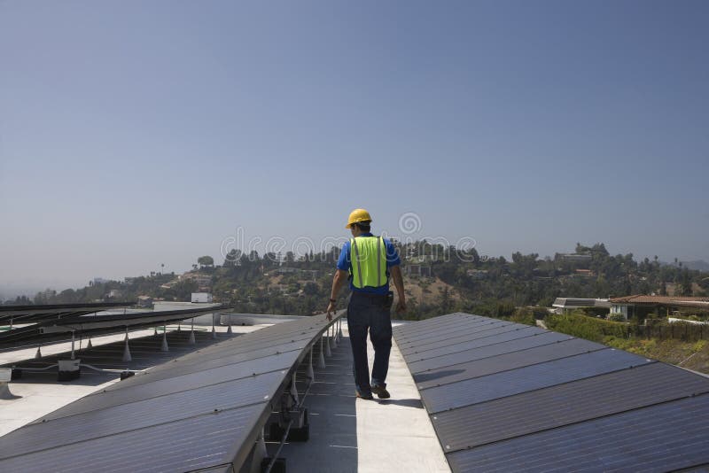 Trabajador del mantenimiento que examina los paneles solares en tejado