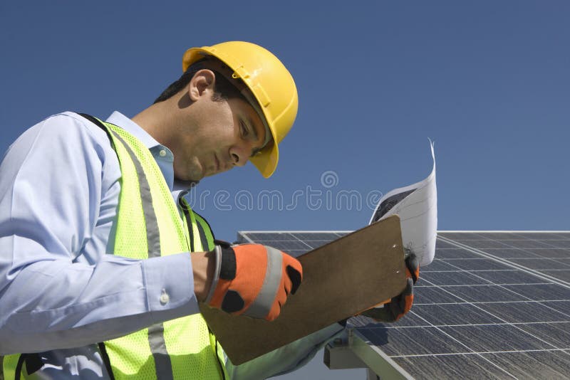 Trabajador del mantenimiento que mira el tablero cerca de los paneles solares
