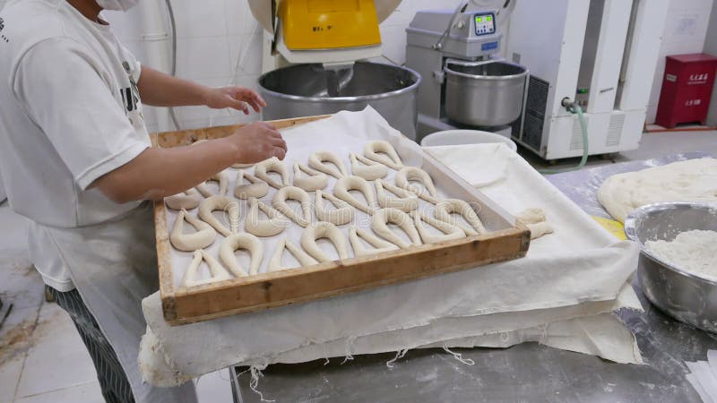 Trabajador en la panadería industrial que prepara los pretzeles para cocer
