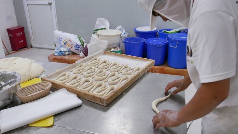 Trabajador en pretzeles industriales de la pasta del balanceo de la panadería