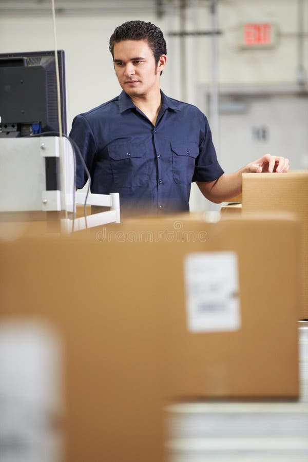 Trabajador que comprueba mercancías en la correa en la distribución Warehouse fotografía de archivo libre de regalías Trabajador que comprueba mercancías en la correa en la distribución Warehouse fotografía de archivo libre de regalías