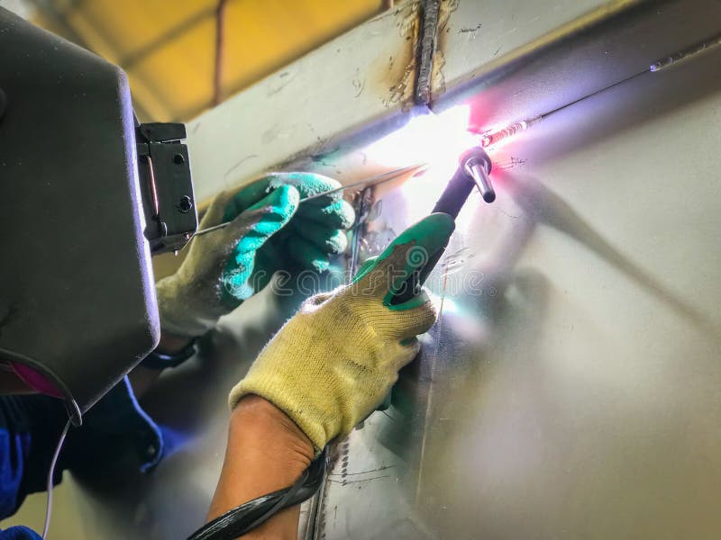 Trabajador que suelda con autógena el tanque inoxidable usando el soldador del tig imagen de archivo Trabajador que suelda con autógena el tanque inoxidable usando el soldador del tig imagen de archivo