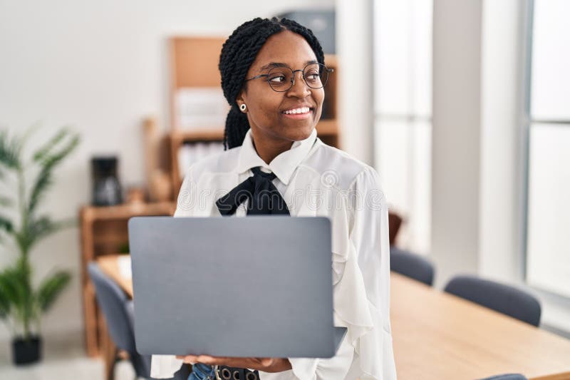 Trabajadora de negocios afroamericana usando laptop trabajando en oficina fotografía de archivo