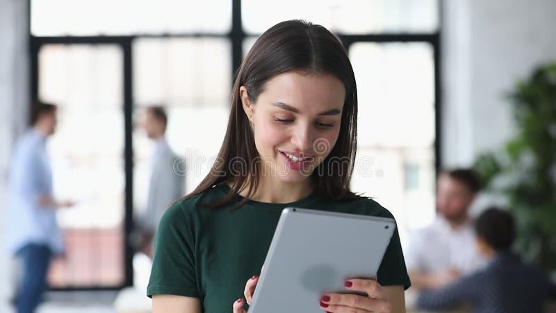 Trabajadora femenina sonriente involucrada en el trabajo en tableta digital