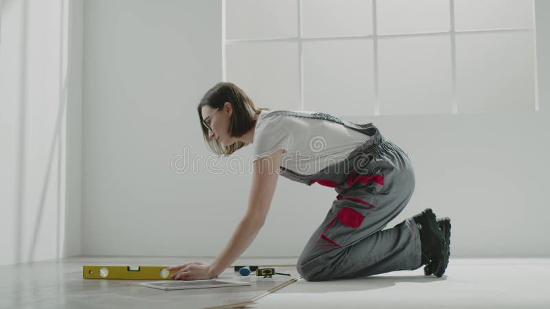 Trabajadora vestida de jumpsuit mide el nivel del piso