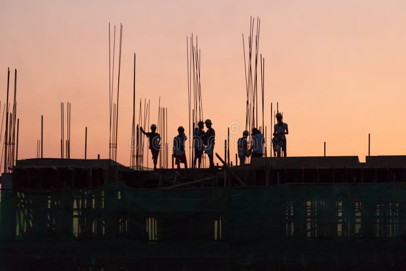 Trabajadores de construcción que trabajan en horas extras imágenes de archivo libres de regalías Trabajadores de construcción que trabajan en horas extras imágenes de archivo libres de regalías