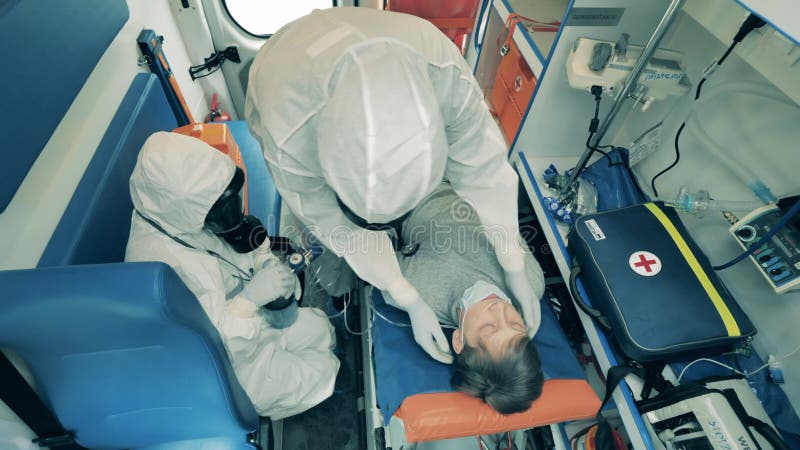 Trabajadores de emergencia ayudan a un hombre en un auto de ambulancia, dándole un ventilador