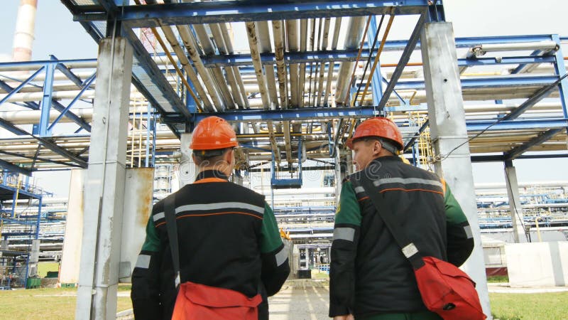 Trabajadores en paseo uniforme bajo opinión de la parte trasera de la tubería