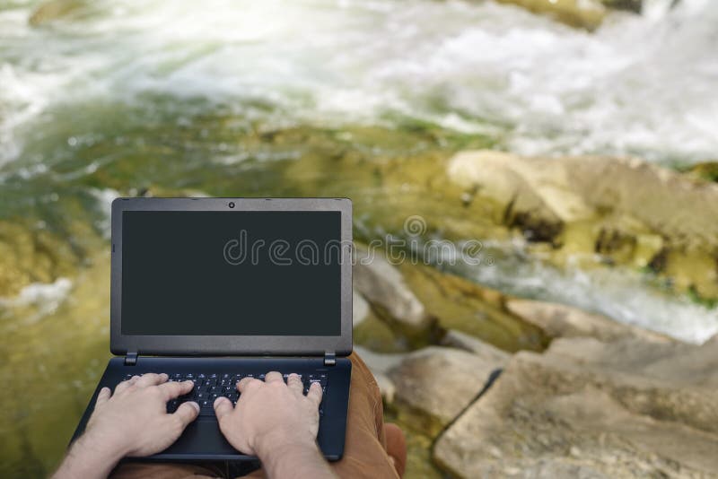 Trabajo en concepto de la naturaleza Las manos de los hombres en el teclado del ordenador portátil en el fondo de un río de la mo fotografía de archivo Trabajo en concepto de la naturaleza Las manos de los hombres en el teclado del ordenador portátil en el fondo de un río de la mo fotografía de archivo