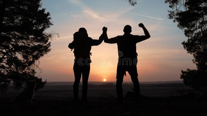 Trabajo en equipo. negocio un concepto de viaje. feliz equipo de turistas hombre y mujer la silueta de la puesta de sol entrega tr