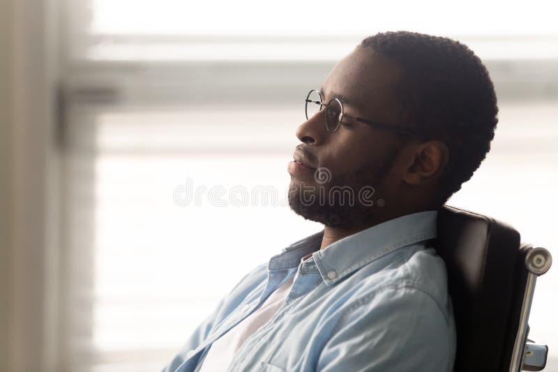 Trabalhador africano sentado em cadeira de escritório ergonômica no local de trabalho