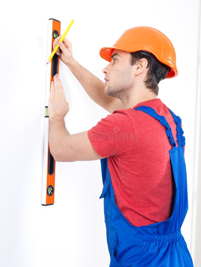 Construction worker with level on the wall over white background - manual worker images. Construction worker with level on the wall over white background - manual worker images.