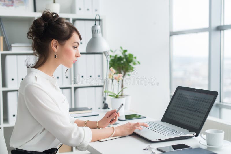 Trabalhador de escritório fêmea que usa o portátil em seu local de trabalho, informação da consultação, surfando o Internet, retr imagem de stock royalty free Trabalhador de escritório fêmea que usa o portátil em seu local de trabalho, informação da consultação, surfando o Internet, retr imagem de stock royalty free