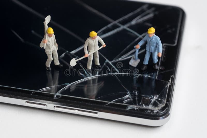 Trabalhador diminuto que trabalha em tela rachada do smartphone imagem de stock Trabalhador diminuto que trabalha em tela rachada do smartphone imagem de stock