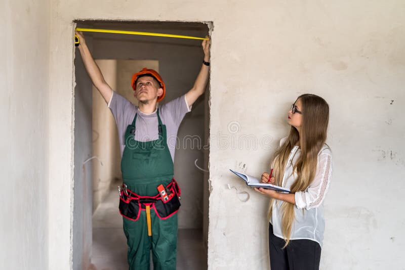 Trabalhador em porta de medida uniforme e mulher em papel fotos de stock royalty free Trabalhador em porta de medida uniforme e mulher em papel fotos de stock royalty free