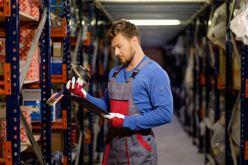 Trabalhador em um armazém das peças sobresselentes imagem de stock Trabalhador em um armazém das peças sobresselentes imagem de stock