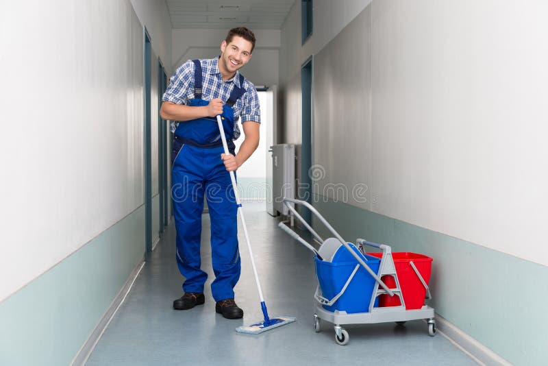 Trabalhador masculino feliz com o corredor do escritório da limpeza da vassoura