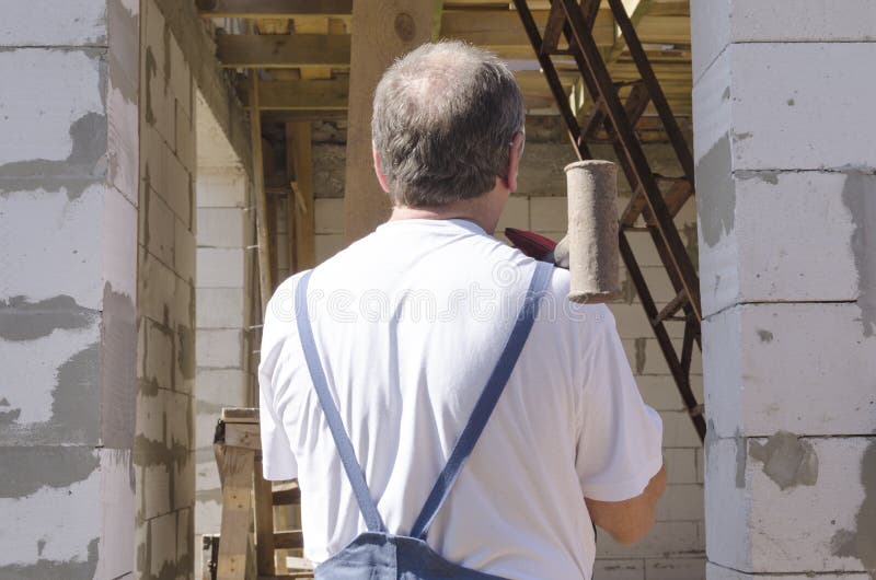 Trabalhador nas costas que segurava martelo metálico Processo de construção de edifícios foto de stock Trabalhador nas costas que segurava martelo metálico Processo de construção de edifícios foto de stock