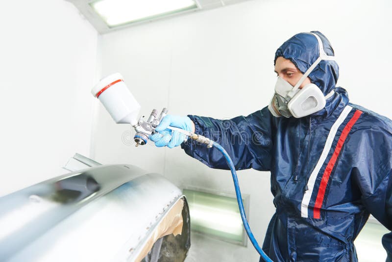 Worker painting auto car bumper using spray gun in a paint chamber during repair work. Focus on pulverizer. Worker painting auto car bumper using spray gun in a paint chamber during repair work. Focus on pulverizer