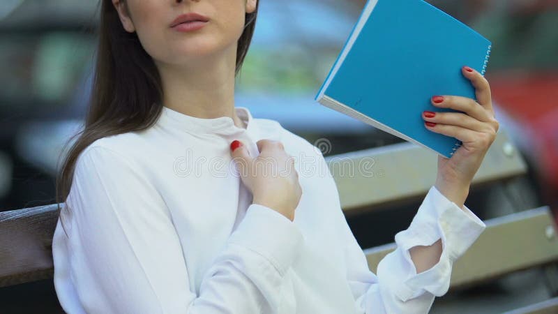 Trabalhadora de escritório sentada no banco sofrendo com o caderno de calor, verão na cidade