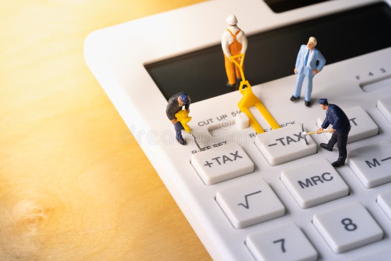 Trabalhadores diminutos que escavam o botão do imposto na calculadora foto de stock Trabalhadores diminutos que escavam o botão do imposto na calculadora foto de stock