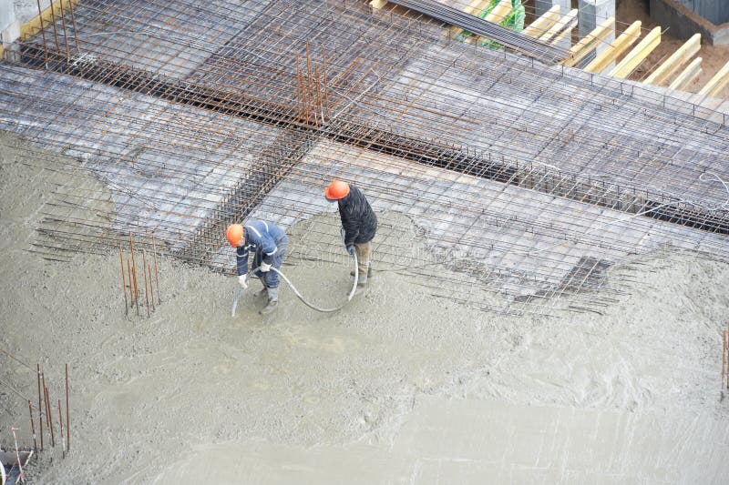Trabalhadores do construtor no trabalho de derramamento concreto