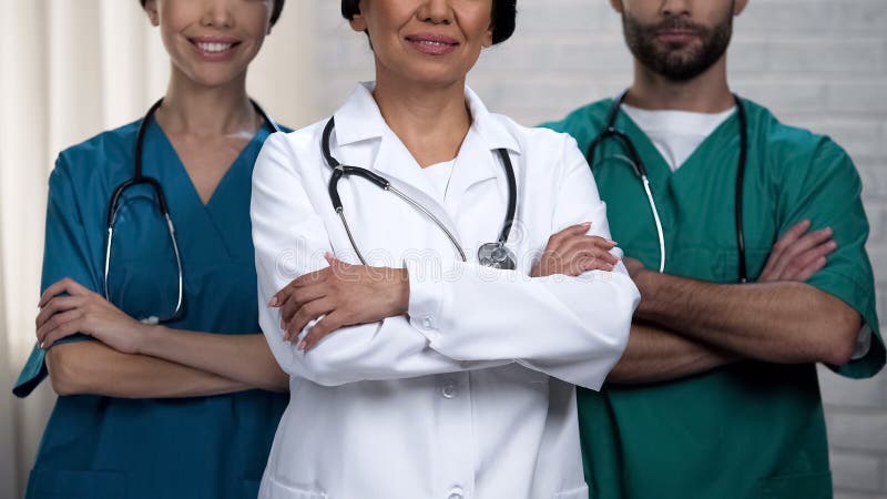 Trabalhadores médicos amigáveis que cruzam as mãos, prontas para ajudar, pessoal altamente qualificado imagens de stock royalty free Trabalhadores médicos amigáveis que cruzam as mãos, prontas para ajudar, pessoal altamente qualificado imagens de stock royalty free