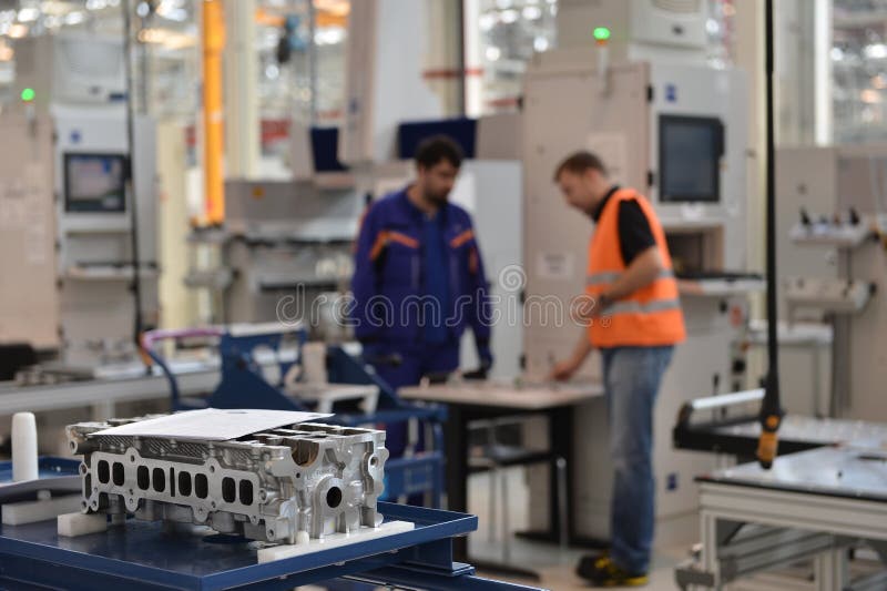 Spare parts in auto engines factory with workers in the background. Spare parts in auto engines factory with workers in the background