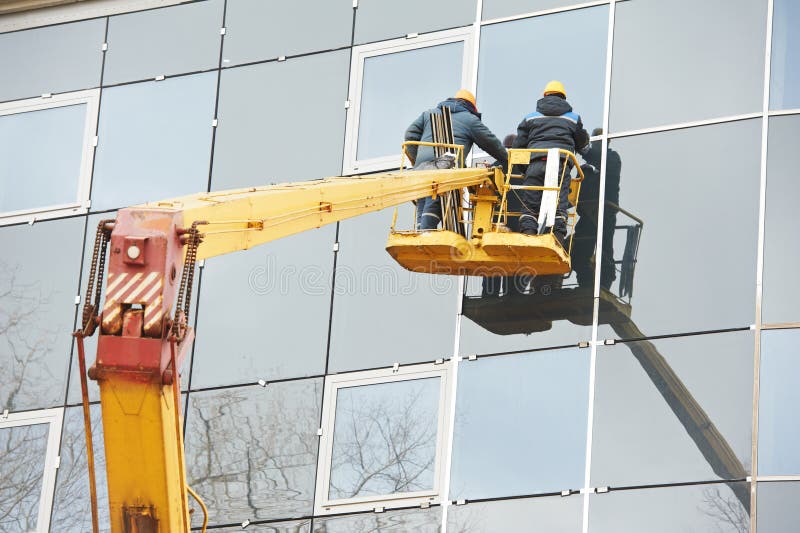 Trabalhadores que instalam a janela de vidro na construção