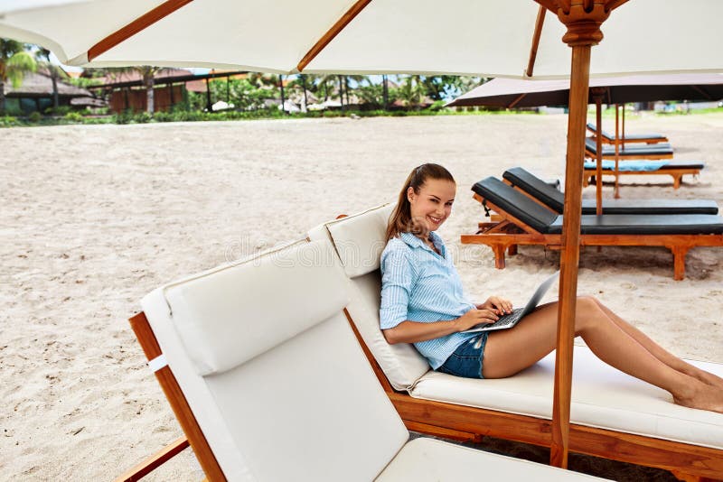 Trabalho do verão Mulher que relaxa usando o computador na praia freelance foto de stock Trabalho do verão Mulher que relaxa usando o computador na praia freelance foto de stock