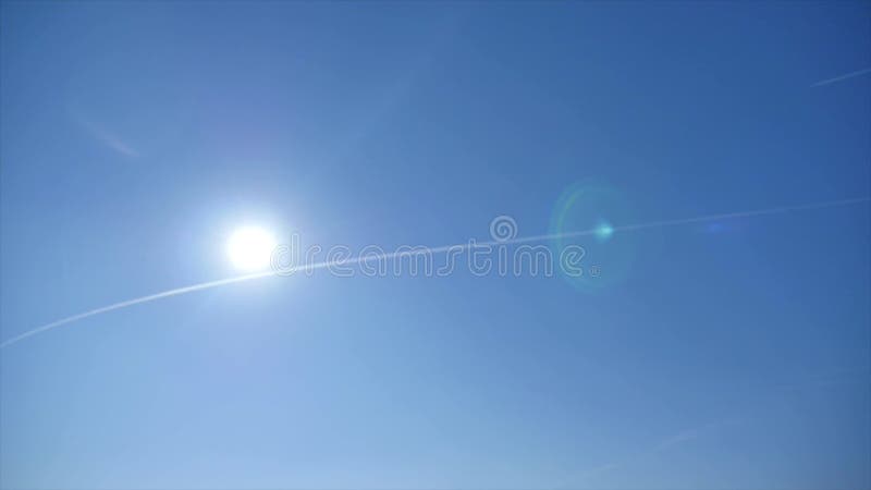 Traccia dell'aeroplano attraverso il cielo blu con il sole