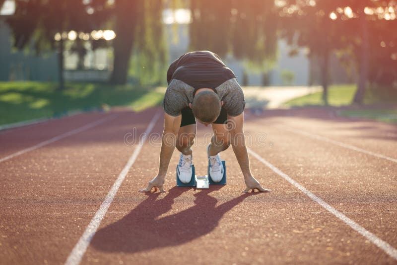 Track runner in starting position on sunny morning. Foot, person.