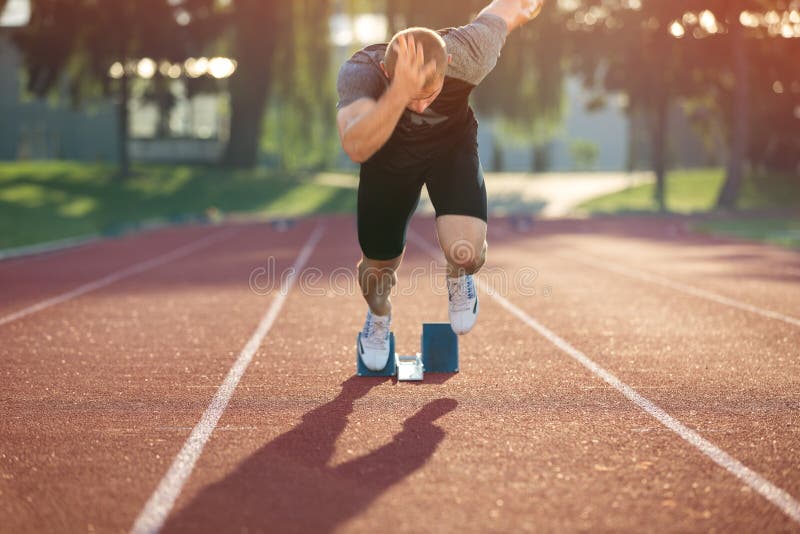 Track runner in starting position on sunny morning. Event, healthy.