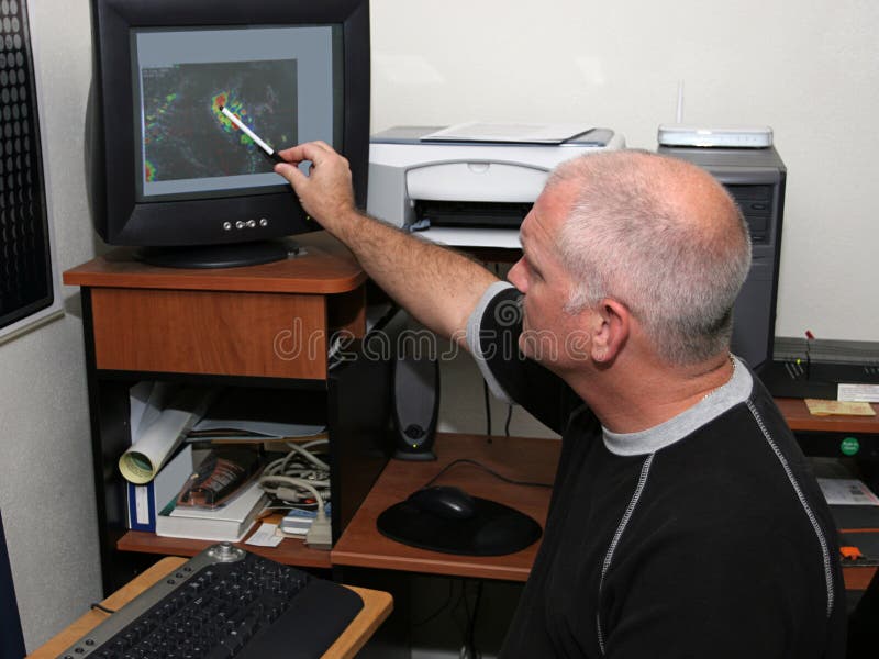 Un meteorologo per il monitoraggio di un uragano sul suo computer e che punta l'occhio.