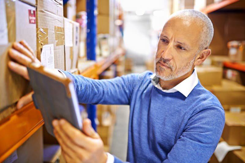 Tracking Your Order Online. a Mature Man Working Inside in a Distribution Warehouse. Stock Photo