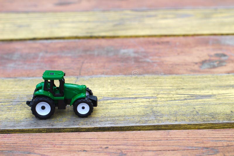 Tractor Del Verde Del Juguete En Una Tabla De Madera Amarillo-roja Imagen de archivo - Imagen de juguete, madera: 148369149